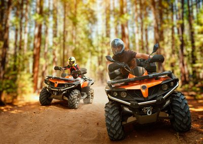 Two atv riders, speed race in forest, front view